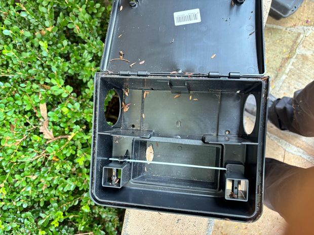 Lockable external rodent bait station opened for servicing beside a garden bed at a Hunters Hill commercial property